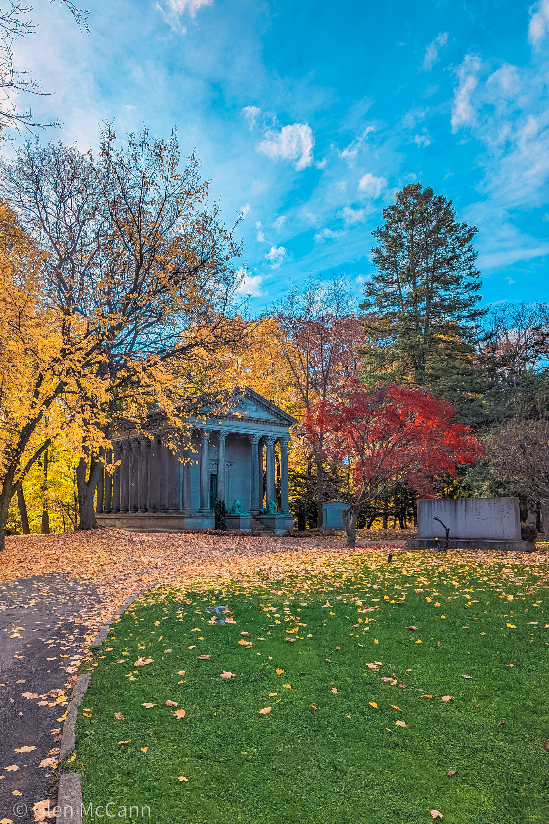 Photo of a mausoleum in a large cemetery in the fall.