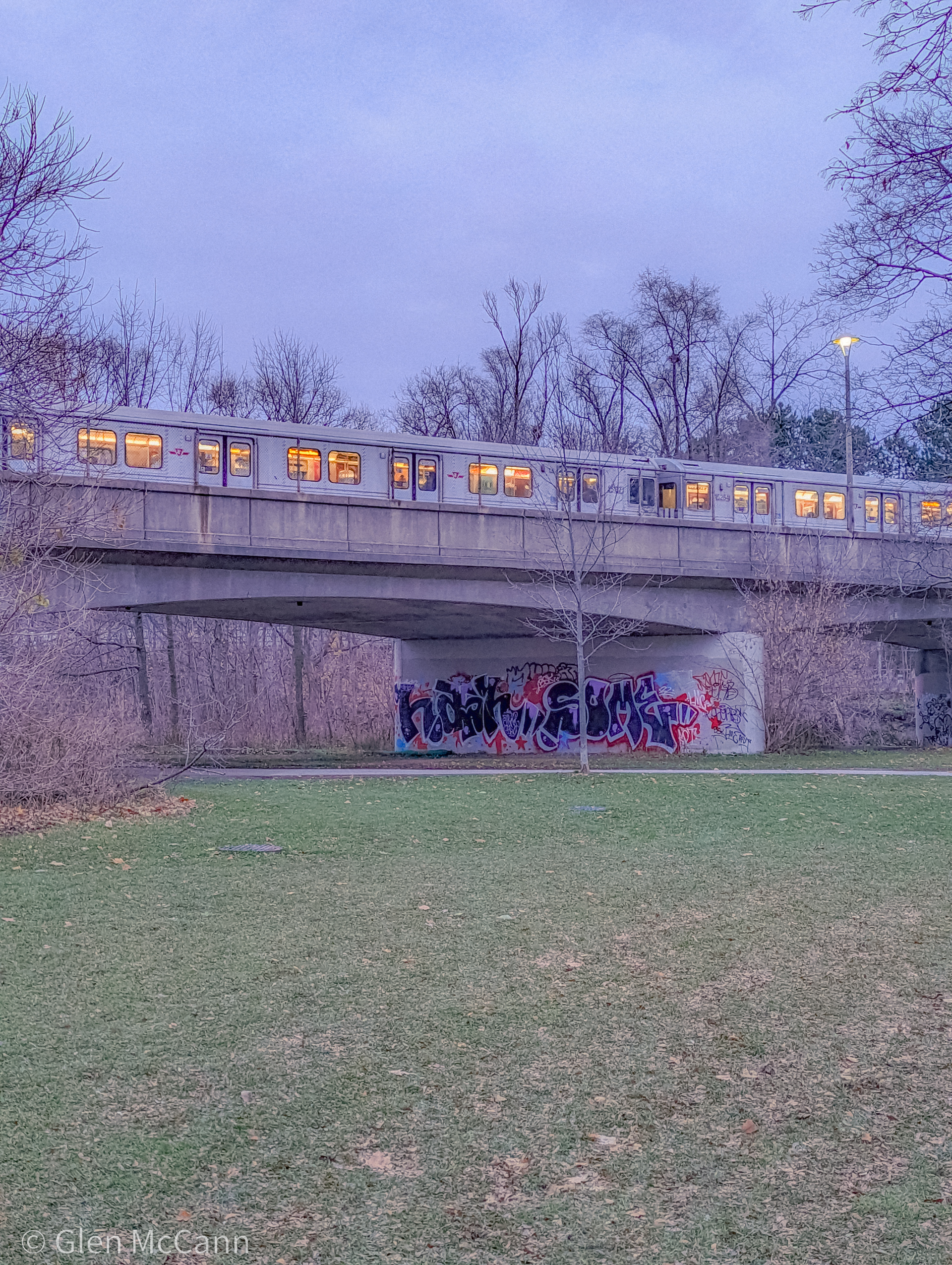Outdoor photo of a Toronto subway car at dusk, the light from the windows causing a glow against a purple sky.