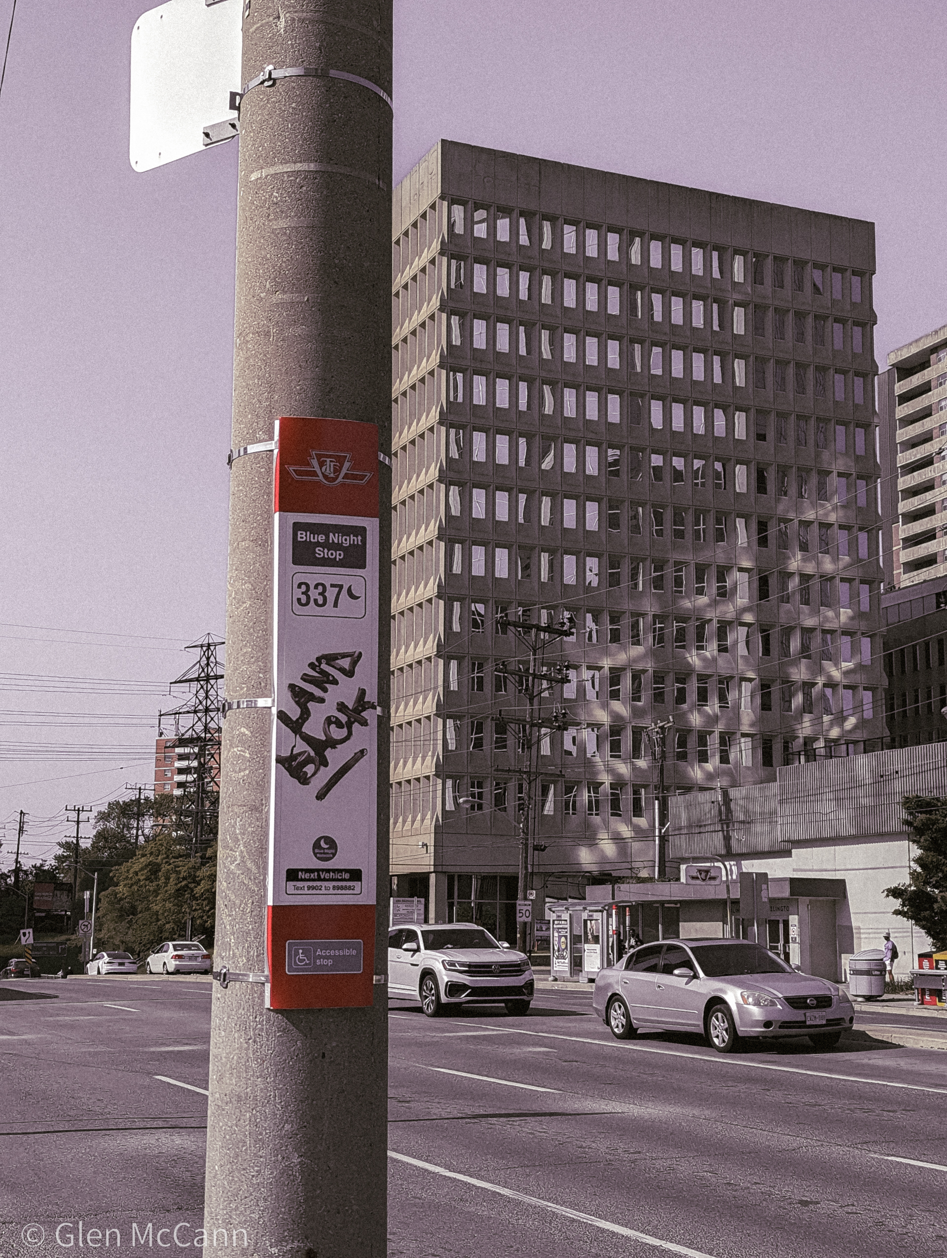 Photo of a TTC bus stop that has 'LAND BACK' written on it in black marker.