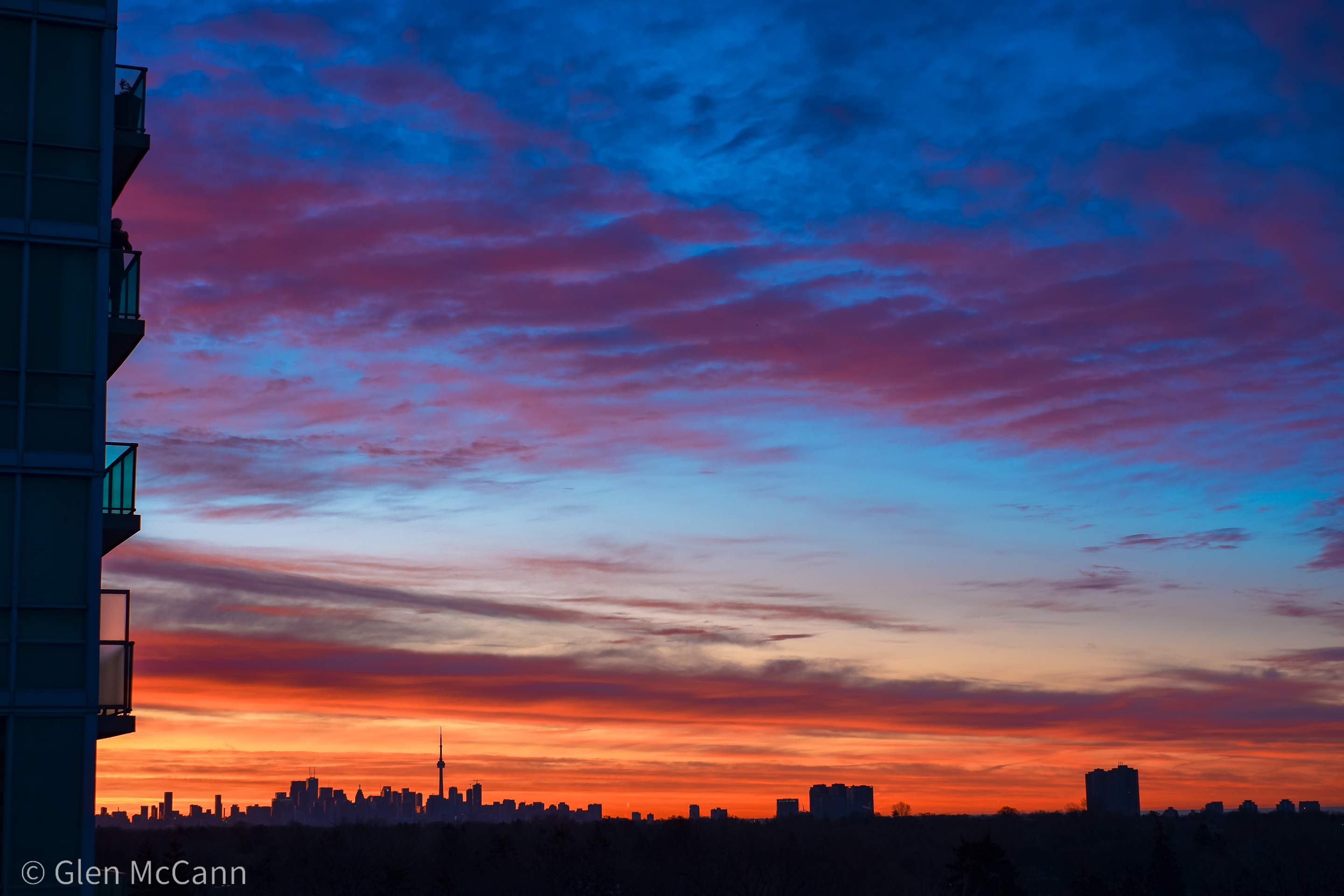 The Toronto skyline during a sunset, viewed from the West and featuring some balconies in the left foreground.